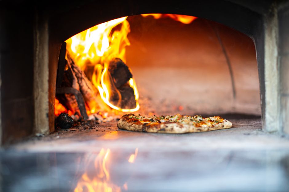 Large gas pizza oven with pizza cooking inside on an outdoor table