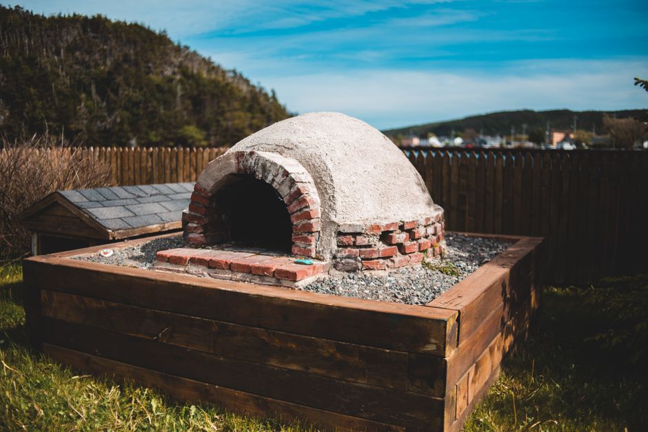 Portable outdoor pizza oven cooking a pizza on a garden patio