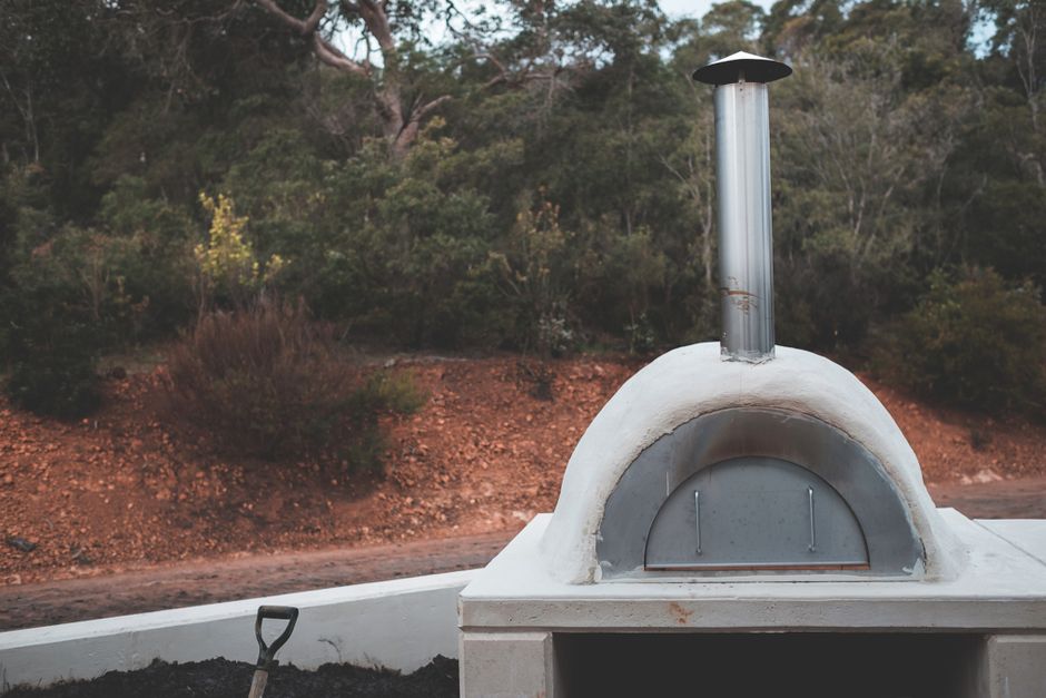 Portable pellet-fired pizza oven in a garden at dusk